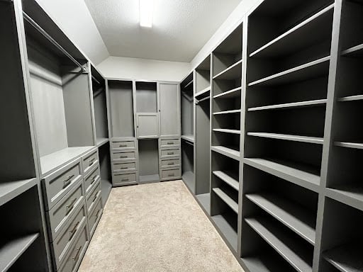 Modern walk-in closet with white and black shelving units, drawers, and hanging rods